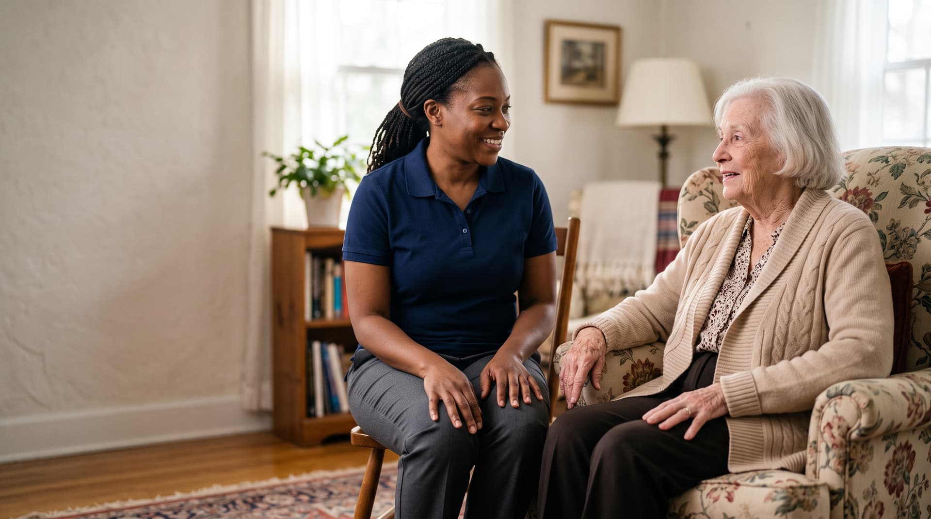A caregiver sitting with a senior at home, offering a calm and reassuring conversation.